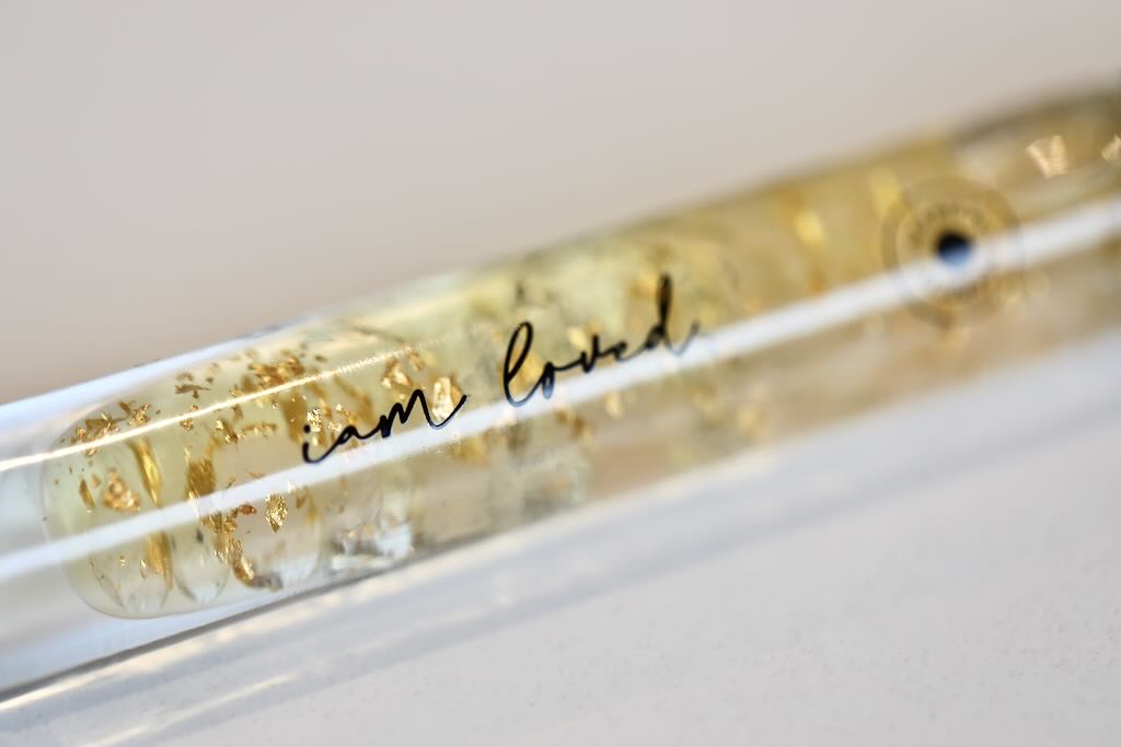 Rose Quartz and clear quartz infused essential oil roller. It reads: I am loved